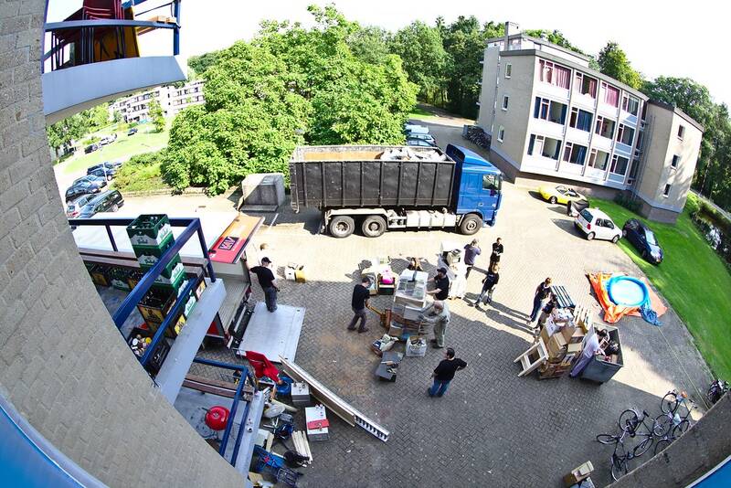 Skip truck with container ready while the crew sorts household items for loading