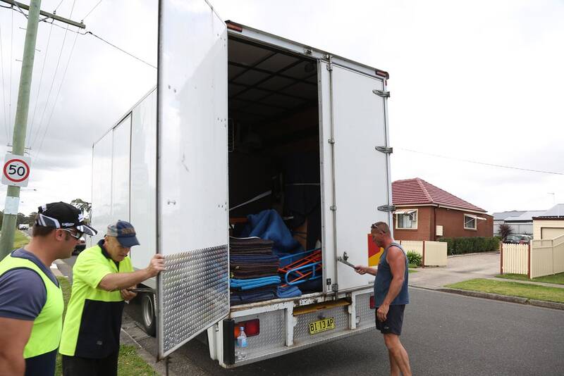 Removal crew opening the back of a furniture truck on a suburban street for a single-item collection