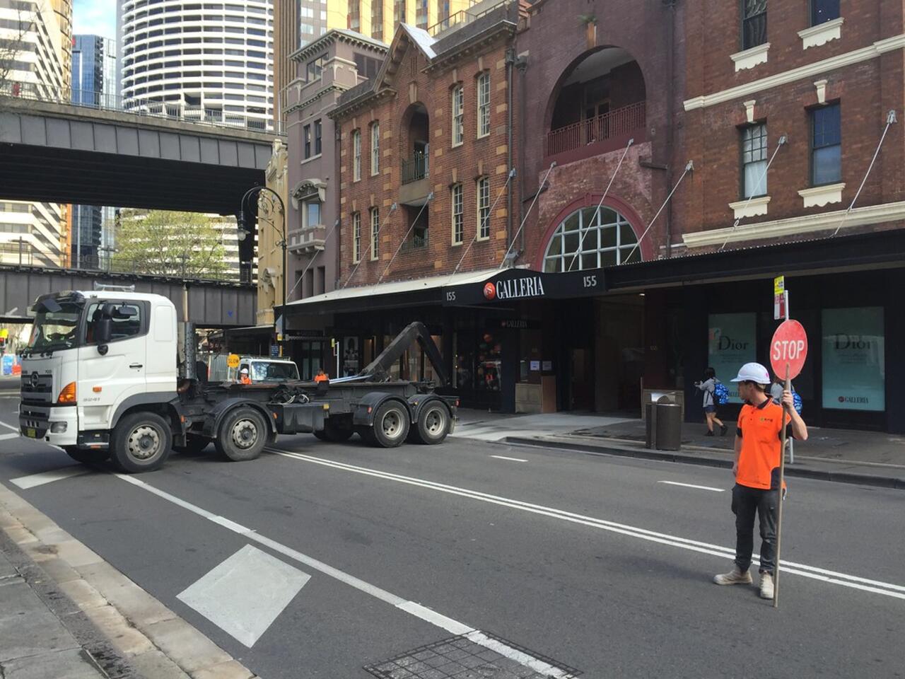 Hook-lift truck collecting a skip bin on a city street — Christchurch Skip Hire runs compact trucks that fit tight Christchurch driveways